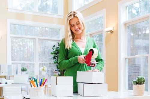 young-woman-packing-boxes-to-be-shipped-in-her-home-office-SBI-3175240452.0